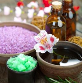 Essential oil supplies, including bottles, bath salts, and a bowl of water with a pink flower