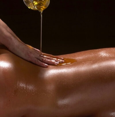 Ayurveda massage with oil pulling onto client's back.