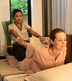 Thai massage therapist holding woman in the plow position of Traditional Thai Massage.